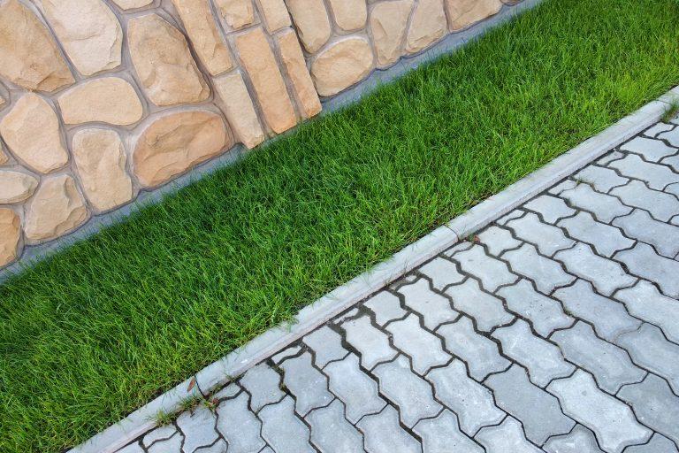 sidewalk paved with cement bricks and green lawn